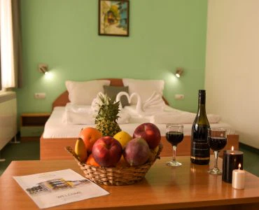 Комфортна стая в хотел Айсберг Банкя с цветна украса, плодове и вино за приятен престой.